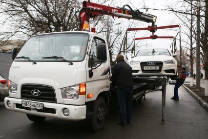 Эвакуатор забирает машину за неправильную парковку.