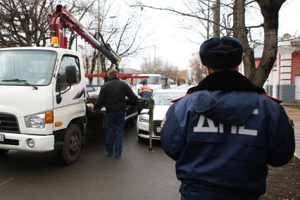 Инспектор ДПС составляет протокол и эвакуирует машину за неправильную парковку.