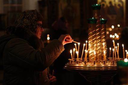 Женщина зажигает свечку в краснодарском храме Рождества Христова.