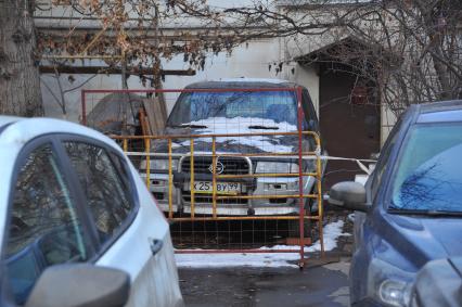 Парковка автомобилей. На снимке: припаркованный автомобиль загороженный забором.