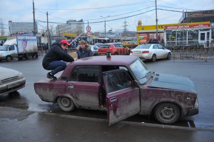 Мужчина сидит на багажнике автомобиля.