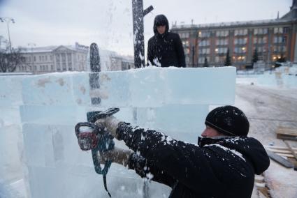 Рабочий бензопилой отрезает излишки льда. Возведение ледового городка на площади 1905 года в Екатеринбурге