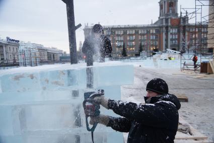 Рабочий бензопилой отрезает излишки льда. Возведение ледового городка на площади 1905 года в Екатеринбурге