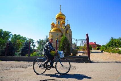 Донецк. Мужчина едет на велосипеде с бутылками воды, которую он набрал в святом источнике в храме.