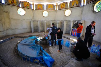 Донецк. Люди набирают воду в святом источнике в храме.