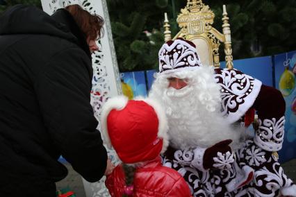 Дед мороз слушает пожелания ребенка во время парада Дедов Морозов в Краснодаре. Площадь Пушкина