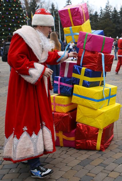 Дед Мороз учавствует в конкурсе, задача которого сложить пирамиду из подарков. Парад Дедов Морозов в Краснодаре, пл. Пушкина