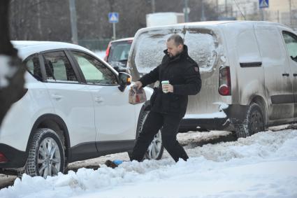 Последствия снегопада в Москве. На снимке: водитель в бахилах с пакетами из Макдоналдса подходит к автомобилю.