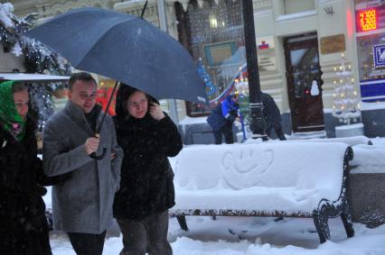 Снегопад в Москве. На снимке:  мужчина и женщина под зонтом.