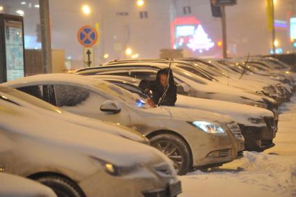 Последствия снегопада в Москве. На снимке: женщина счищает снег с машины.