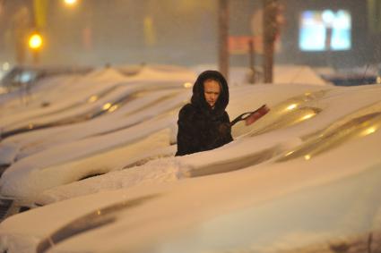 Последствия снегопада в Москве. На снимке: женщина счищает снег с машины.