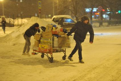 Снегопад в Москве. На снимке: гастарбайтеры везут тележку с пустыми коробками.