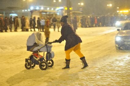 Снегопад в Москве. На снимке: женщина с детской коляской переходит дорогу.