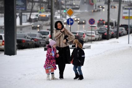 Снегопад в Москве. На снимке: женщина с детьми идут по улице.