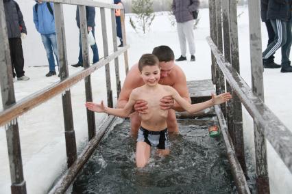 Крещенские купания в Барнауле. На снимке: мужчина окунает ребенка в купели на реке Обь.