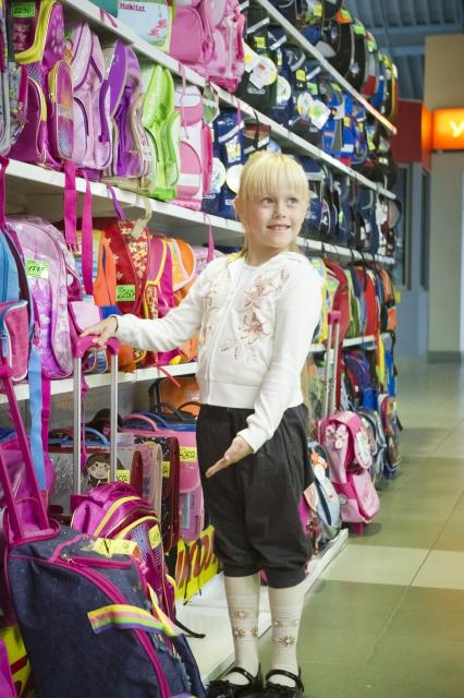 девочка выбирает школьный портфель в магазине. Школьный базар
