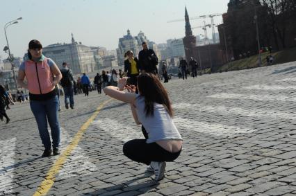 Девушка фотографирует подругу на Красной площади.