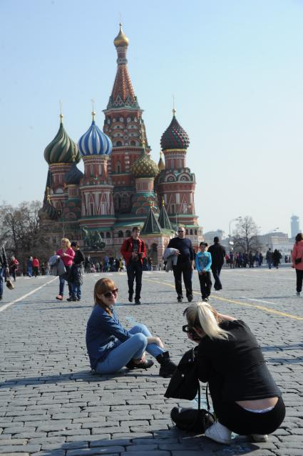 Девушка фотографирует подругу на фоне Храма Василия Блаженного на Красной площади.