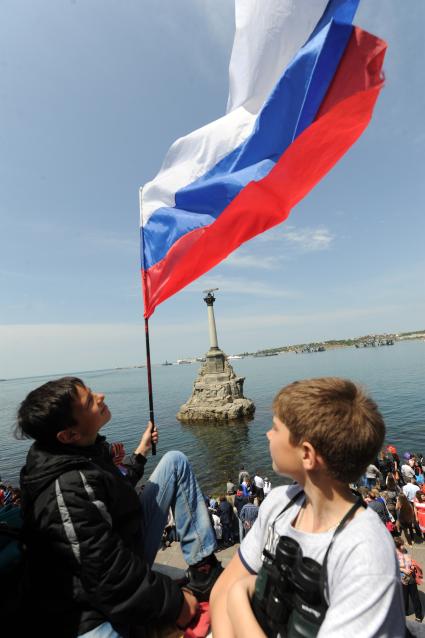 Севастополь. День Победы. На снимке: подростки держат российский флаг на фоне памятника затопленным кораблям.