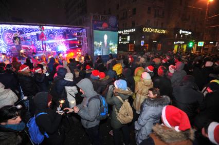 Празднование Нового года на Тверской улице в Москве. На снимке: люди на улице слушают новогоднее поздравление президента РФ Путина.