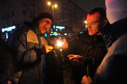 Празднование Нового года на Тверской улице в Москве. На снимке: молодые люди  поджигают бенгальский огонь.