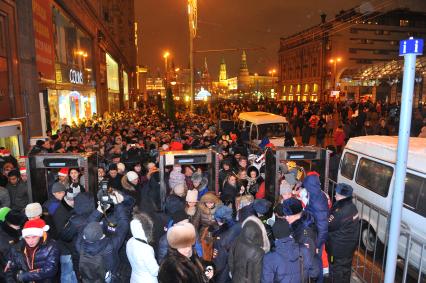 Празднование Нового года на Тверской улице в Москве. На снимке: люди проходят через рамки металлоискателя.