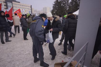 Полицейский досматривает мужчину, пришедшего на митинг вкладчиков финансовой пирамиды  МММ в Екатеринбурге