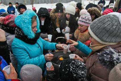 Женщина разливает чай толпе ребят на улице