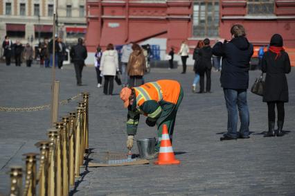 Красная площадь. На снимке: женщина красит дождевую решетку.