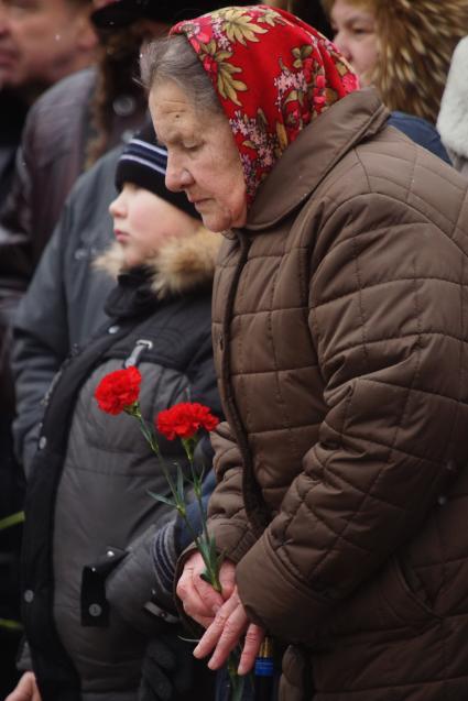 пожилая женщина держит букет гвоздик, во время вахты памяти войнов погибших в афганистане, у памятника войнам-интернационалистам \"Черный тюльпан\" в Екатеринбурге