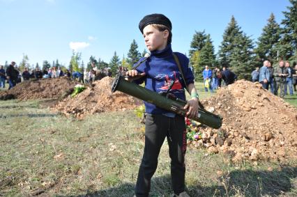 Украина. Донецкая область. Курган Саур-Могила. Похороны 17 ополченцев и захоронение останков 82 солдат Второй мировой войны. На снимке: мальчик с противотанковым оружием.