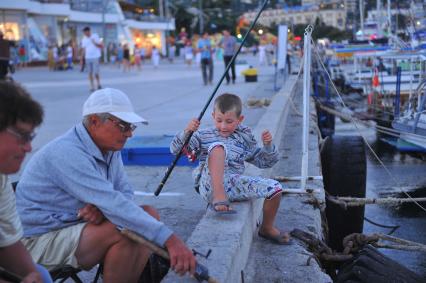 Ялта. Пляж. На снимке: рыбаки на набережной ловят рыбу с удочкой.