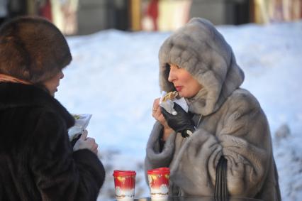 Блинная ярмарка на Кузнецком мосту в Москве.  На снимке: женщина кушает блин.