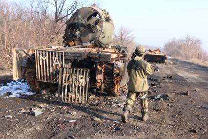 Украина. Донецкая область. г.Углегорск. На снимке: ополченец на фоне сгоревшей военной техники.