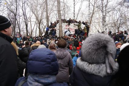 Молодые парни штурмом берут снежную стену. Празднование Масленицы в Харитоновском парке, в Екатеринбурге