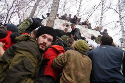 Молодые парни штурмом берут снежную стену. Празднование Масленицы в Харитоновском парке, в Екатеринбурге