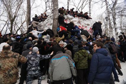 Молодые парни штурмом берут снежную стену. Празднование Масленицы в Харитоновском парке, в Екатеринбурге