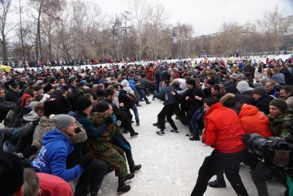 Молодые парни и мужчины участвуют в народной забаве \"Стенка на стенку\". Празднование Масленицы в Харитоновском парке, в Екатеринбурге