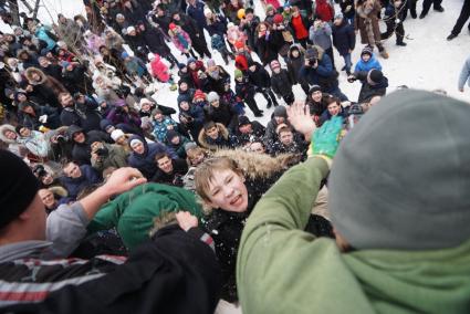 Молодые парни штурмом берут снежную стену. Празднование Масленицы в Харитоновском парке, в Екатеринбурге