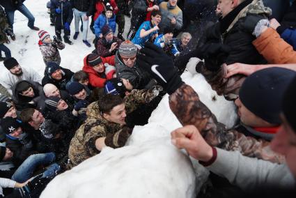 Молодые парни штурмом берут снежную стену. Празднование Масленицы в Харитоновском парке, в Екатеринбурге