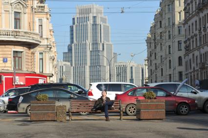 Аномально теплая зима в Москве. Мужчина курит на Триумфальной площади. На заднем плане - бизнес-центр `Оружейный`.