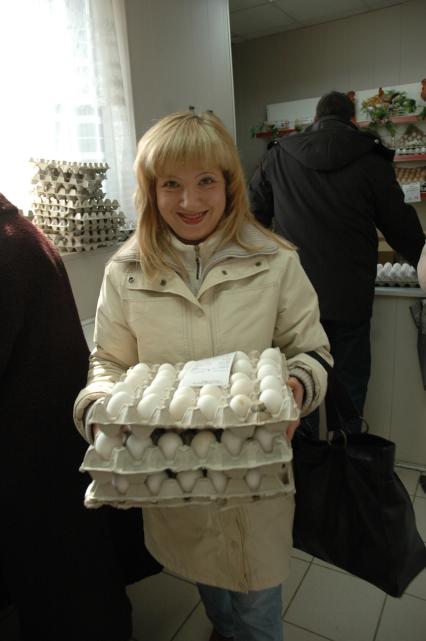 Женщина несет куриные яйца в поддоне