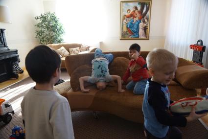 Многодетная семья православных верующих Афанасьевых, с их приемными детьми. Дети играют в гостиной. Поселок Октябрьский Свердловской области