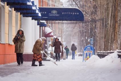 Женщина-дворник убирает снег с тротуара. Екатеринбург