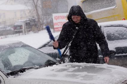 Водитель чистит машину от снега, во время мартовского снегопада. Екатеринбург