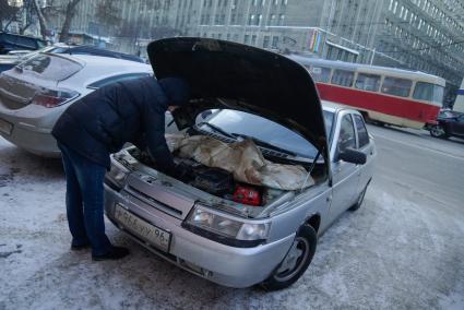 водитель согревает двигатель автомобиля, во время сильных морозов в Екатеринбурге