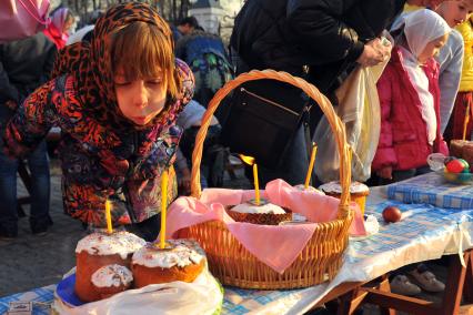 Пасха. Девочка задувает свечку на освященном куличе.