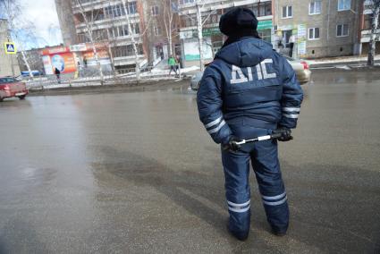 Сотрудник ДПС с жезлом стоит на дороге. Совметный рейд ГИБДД и МЧС по проверке наличия и исправности огнетушителей в автомобилях