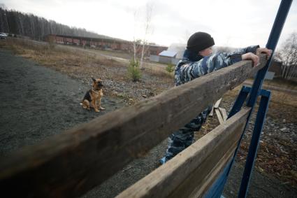 Девушка-полицейский кинолог с своей служебной собакой во время преодоления полосы препядствий. Уральский кинологический центр