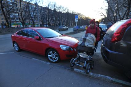 Москва. Женщина с детской коляской проходит мимо припаркованных машин.